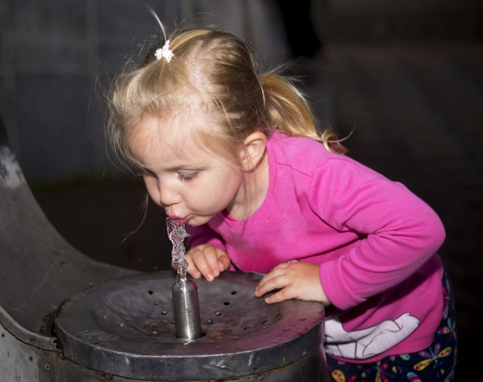 little girl drinking from water fountain