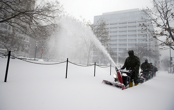 US Park Service employees clean snow off sidewalk with snow blower